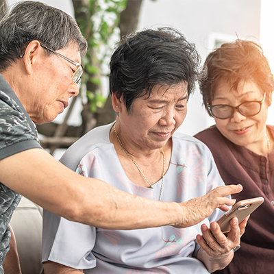 A mobile screen is being watched by three elderly people