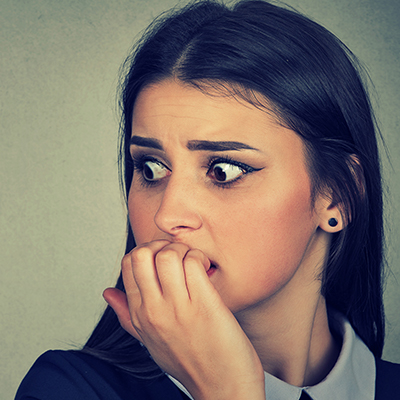 A close-up of a young woman showing fear expressions with her wide open eyes